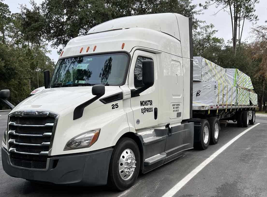Monster Express Inc truck number 25 with flatbed trailer carrying secured cargo